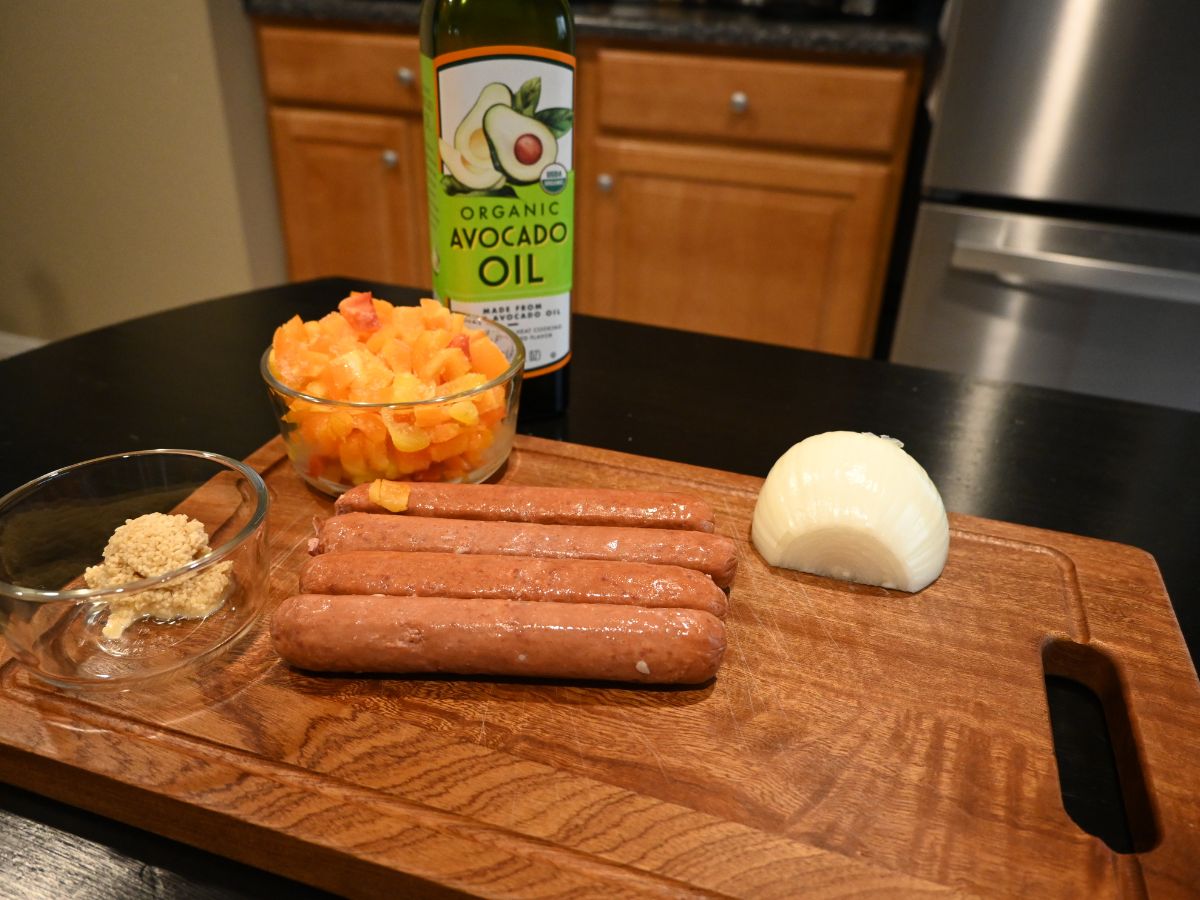 avocado oil with kielbasa sausage, diced bell peppers, diced onions and minced garlic on a cutting board