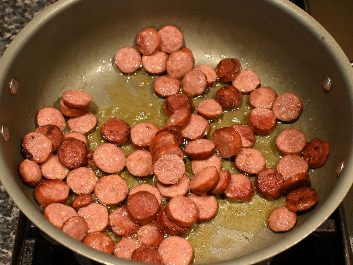 sliced kielbasa frying in a pan