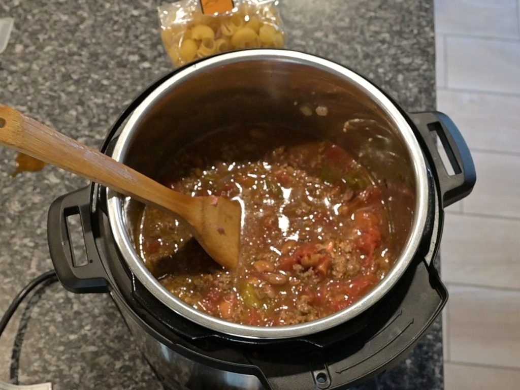 beef broth and diced tomatoes added to cheesy chili mac in the instant pot