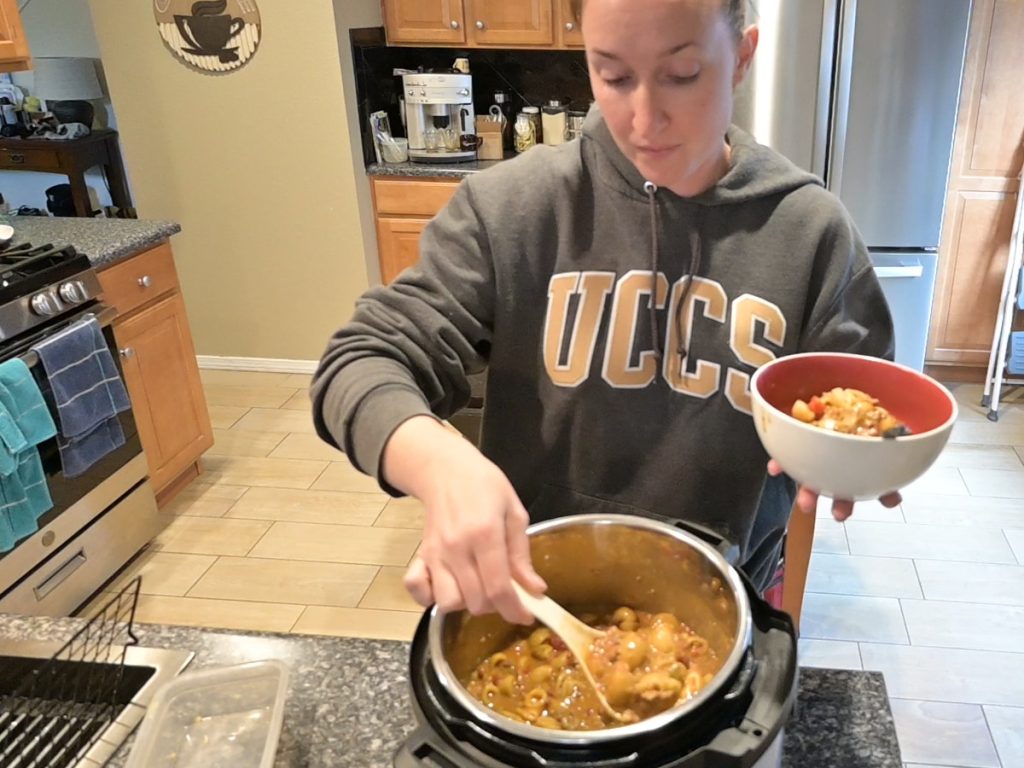 woman scooping cheesy chili mac into a bowl